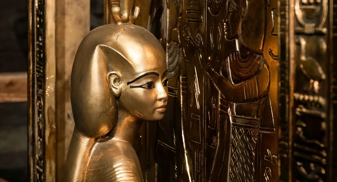 Golden Egyptian statue of a pharaoh beside a detailed hieroglyph-covered wall.