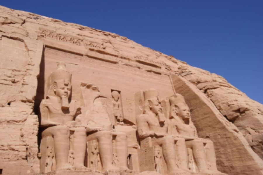 Ancient rock-cut statues of seated figures at Abu Simbel under a clear blue sky.