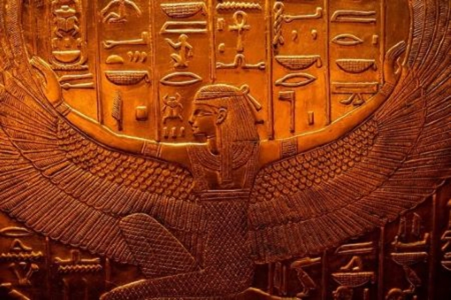 Ancient Egyptian carving of a winged figure with hieroglyphics in the background.